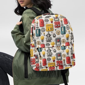 May include: A white backpack with a colorful repeating pattern of robots, gears, and light bulbs. The backpack has black straps and a black handle. The background is white.