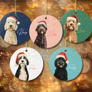 May include: Five circular Christmas decorations with dog portraits wearing Santa hats. Each decoration has a different background colour: navy, pink, green, white, and teal. Names Harry, Bailey, Louie, Roxie, and Rocky are written on each decoration.