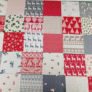 May include: A collection of thirty-five square fabric patches arranged in a grid, featuring various holiday-themed patterns including reindeer, snowflakes, stars, holly, and geometric designs in a colour palette of red, white, grey, and green.