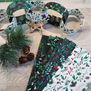 May include: A festive arrangement featuring fabric strips and decorative elements. The strips display a repeating pattern of green leaves, red berries, and white accents. A sprig of pine and pinecones are also present, along with a star-shaped decoration.