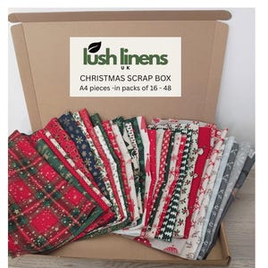 May include: A brown cardboard box filled with assorted A4 fabric pieces featuring Christmas-themed patterns in red, green, white, and grey. The box lid displays the text Lush Linens UK, CHRISTMAS SCRAP BOX, and A4 pieces -in packs of 16 - 48.