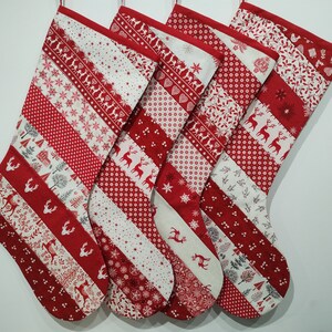 Puede incluir: Cinco calcetines de Navidad rojos y blancos con un diseño de patchwork. Los calcetines presentan varios patrones, incluyendo copos de nieve, renos y árboles.