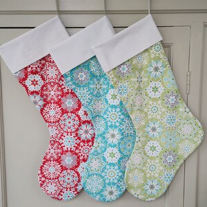 May include: Three Christmas stockings with snowflake patterns. The stockings are red, blue, and green with white trim.