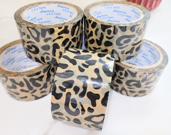 May include: Four rolls of leopard print duct tape. The tape is brown and black with a shiny finish. The tape is labeled "USA TAPE" and "America".