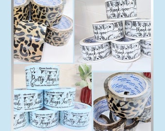 May include: Assortment of clear packing tape rolls with leopard print and blue and white labels. The labels say "Please handle with care Pretty Things Justly" and "Thank you for supporting my business".