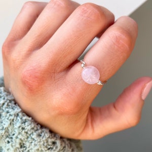 Könnte beinhalten: Ein silberner Ring mit einem rosafarbenen Rosenquarzstein. Der Stein ist rund und hat ein zartes Blumenmuster.