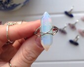 Iridescent opalite double terminated wire wrapped crystal ring on silver tone adjustable base.