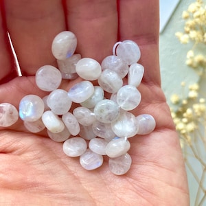 May include: A collection of white moonstone beads, each with a smooth, rounded shape and a subtle iridescent sheen.