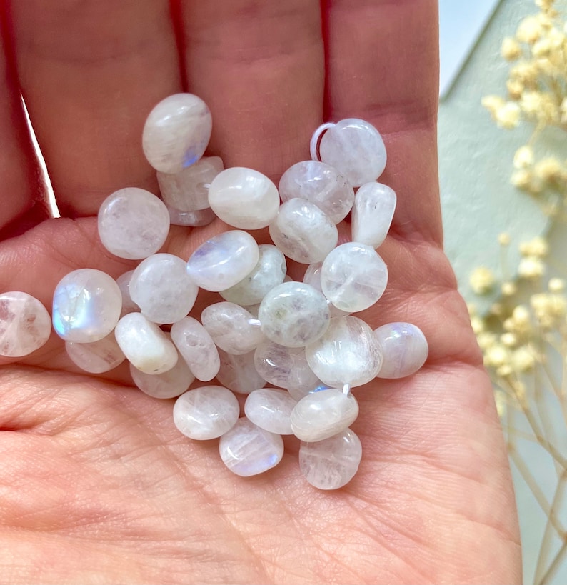 May include: A collection of white moonstone beads, each with a smooth, rounded shape and a subtle iridescent sheen.