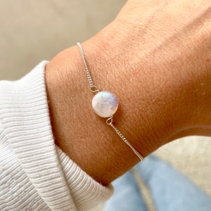 May include: A delicate silver chain bracelet with a single round white moonstone charm.