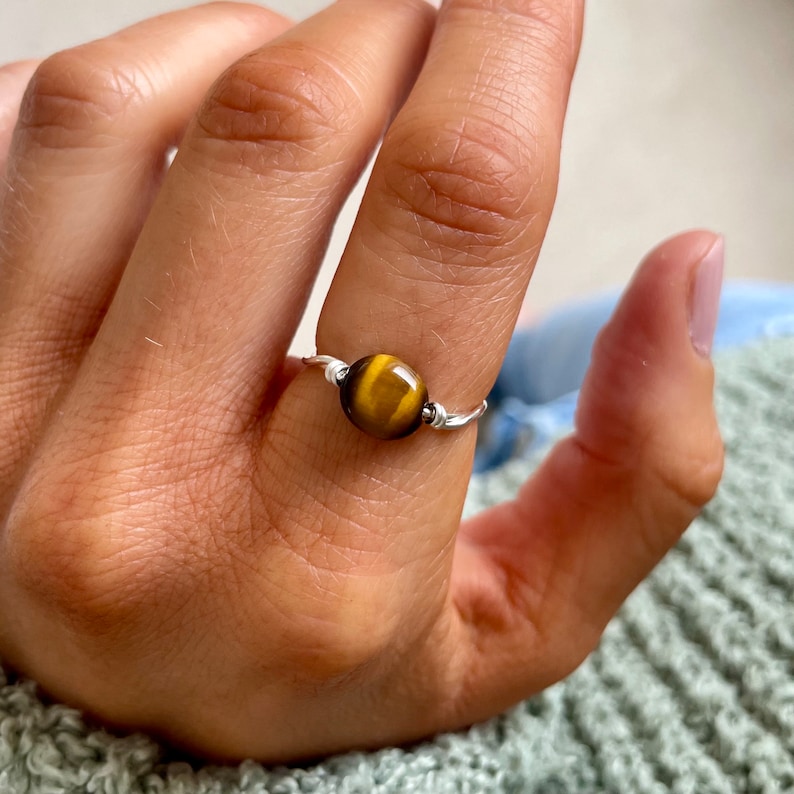 May include: A silver wire ring with a round tiger's eye gemstone.