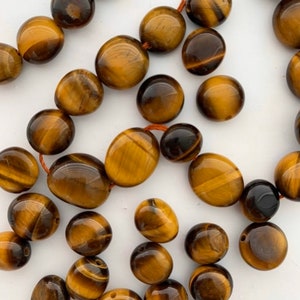 May include: A strand of tiger's eye beads, each bead is a smooth, oval shape with a golden brown color and a shimmering, chatoyant effect.
