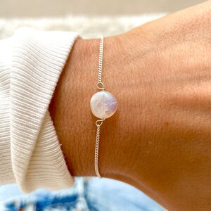 May include: A silver chain bracelet with a single round moonstone charm.