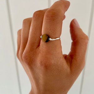 May include: A silver wire ring with a round tiger's eye gemstone.