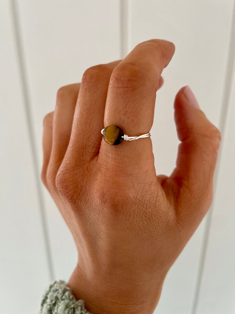 May include: A silver wire ring with a round tiger's eye gemstone.