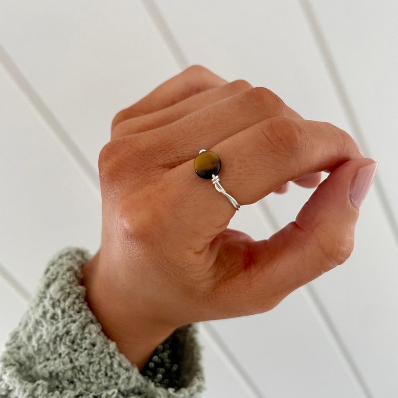 May include: A silver wire ring with a round brown tiger's eye gemstone.