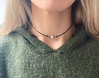 May include: A simple black choker necklace with a small silver diamond-shaped pendant.