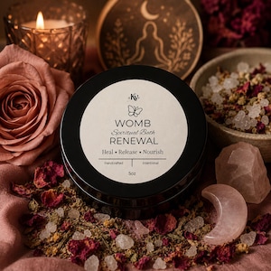 Puede incluir: Un recipiente redondo de color negro con una etiqueta blanca que dice WOMB Spiritual Bath RENEWAL, Heal Release Nourish y 5oz. La etiqueta presenta un icono de mariposa y el logotipo KV. El recipiente está rodeado de pétalos de flores secas, cristales de sal y cuarzo rosa.