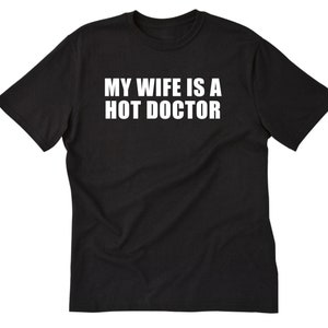 May include: Black t-shirt with white text that reads "My wife is a hot doctor."