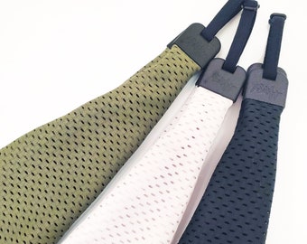 Könnte beinhalten: Drei Mesh-Stirnbänder in Grün, Weiß und Schwarz mit schwarzen verstellbaren Bändern. Die Bänder haben den Schriftzug "Scrunchie" aufgedruckt.