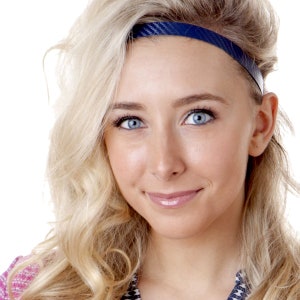 May include: A woman with long blonde hair wearing a blue headband. She is smiling and looking at the camera.