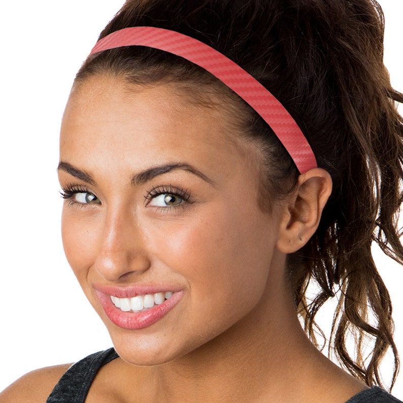 May include: A coral pink headband with a textured, carbon fiber-like pattern. The headband is worn by a person with dark hair.
