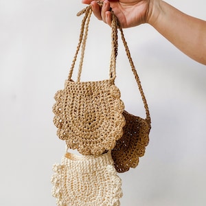 May include: Two crocheted bags with scalloped edges. The larger bag is brown and the smaller bag is white.