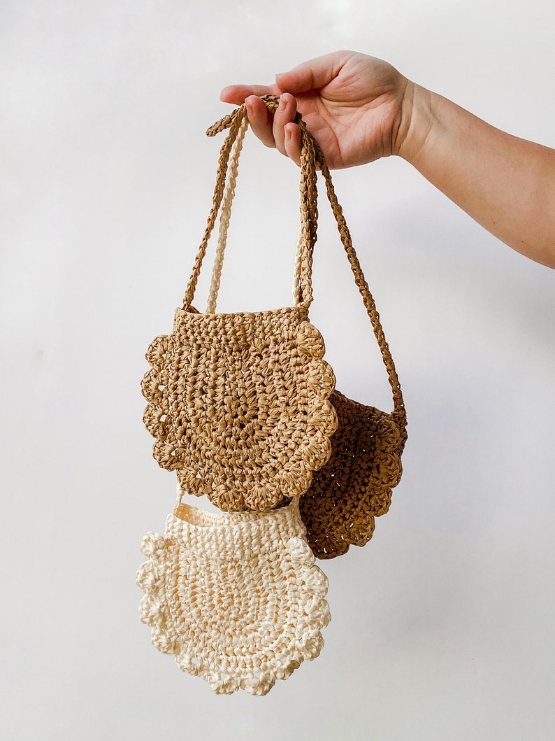 May include: Two crocheted bags with scalloped edges. The larger bag is brown and the smaller bag is white.