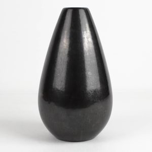Könnte beinhalten: Eine schwarze Keramikvase mit glatter, glänzender Oberfläche. Die Vase hat die Form einer Träne und eine schmale Öffnung.