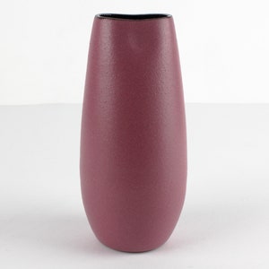 May include: A tall, slender vase in a deep, rich burgundy colour. The vase has a smooth, slightly textured surface and a black rim.