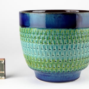 May include: A set of three ceramic mugs with a speckled, matte finish. The mugs are in shades of cream, light gray, and dark gray. Each mug has a simple, minimalist design, suitable for coffee or tea.