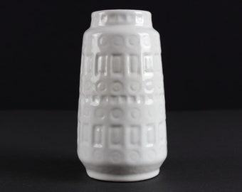 May include: White ceramic vase with a textured geometric pattern. The vase has a cylindrical shape and a slightly flared opening.