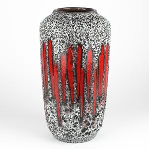 Könnte beinhalten: Eine Keramikvase mit einem gesprenkelten grauen und schwarzen Überzug und rotem Tropf-Überzug. Die Vase ist hoch und zylindrisch.