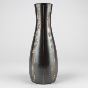 May include: A black ceramic vase with a gold geometric pattern. The vase has a narrow neck and a wide base.