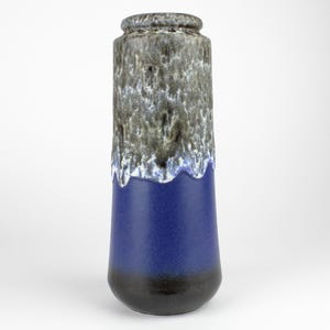 Könnte beinhalten: Eine hohe, blaue und graue Keramikvase mit einem Tropf-Glazureffekt. Die Vase hat einen breiten Boden und einen schmalen Hals.