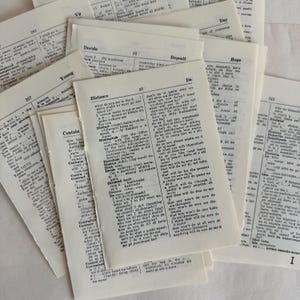 Puede incluir: Una colección de páginas de diccionario antiguas, algunas con texto visible, están dispersas. Las páginas están amarillentas, lo que sugiere la edad, y el texto es negro. La palabra "Distance" es visible en una página.