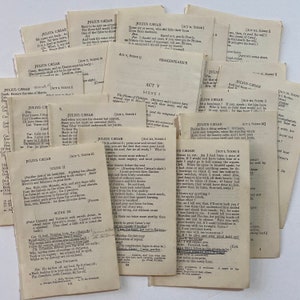 May include: Close-up of a collection of vintage paperbacks of Shakespeare's play Julius Caesar. The pages are yellowed with age and the text is printed in black ink. The covers are simple and feature the title of the play and the author's name.