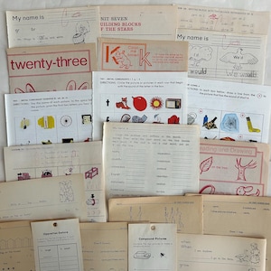 May include: A collection of vintage educational worksheets, featuring handwriting practice, phonics, and simple math problems. The papers are aged with text and illustrations in black and red ink. The worksheets are designed for early elementary students.