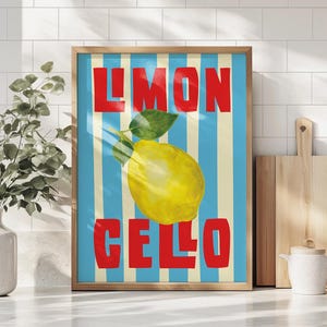 May include: A framed art print with a yellow lemon and green leaves set against blue and cream stripes. The words "LIMON CELLO" are in bold red text. The artwork is displayed on a white countertop.