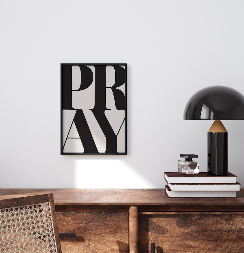 Minimalist PRAY typography wall art in a white frame, styled above a wooden desk in a minimalist, clean, tidy home office space