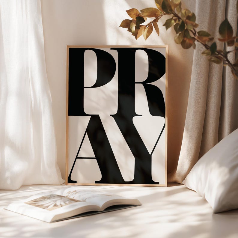 Modern Christian wall art print with the word ‘PRAY’ in bold black typography on a white background in a prayer space, soft neutral bedroom decor. statement wall art piece for faith-filled homes. Scripture print poster for prayer rooms and church spaces.