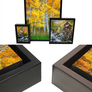 May include: Framed canvas art prints featuring scenic landscapes. The images showcase vibrant autumn foliage and a rustic cabin. Available in black or brown frames. The text reads "Framed Premium Quality Canvas" and "Artwork comes ready to hang."