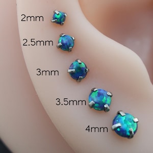 May include: A close-up of a series of opal stud earrings in various sizes, ranging from 2mm to 4mm. Each earring features a vibrant blue-green opal stone set in a silver-colored metal. The sizes are labeled on the left side of the image.