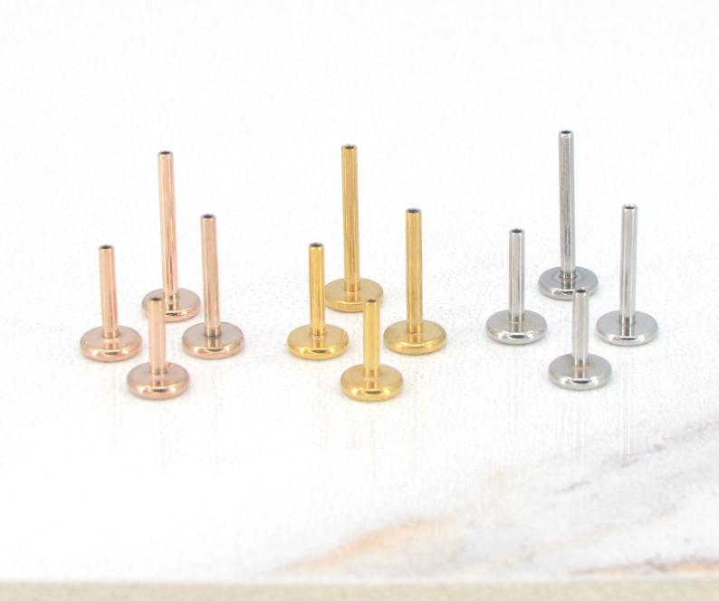 May include: A set of 10 surgical steel body jewelry studs in three colors: gold, rose gold, and silver. The studs are available in different lengths and are ideal for cartilage piercings, helix piercings, and lobe piercings.