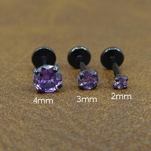 May include: Three black labret studs with purple gemstones. The studs are labeled with sizes: 4mm, 3mm, and 2mm. The gemstones are round and faceted, set in a black metal setting.