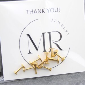 May include: A collection of gold-colored metal labret studs with flat back discs, packaged in a clear plastic sleeve against a white display card featuring the black text THANK YOU! and the logo MR JEWELRY in a circular frame.