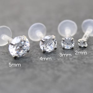 May include: Four clear lip piercing studs with clear backs. The studs have silver settings and clear, round gemstones. Sizes are 2mm, 3mm, 4mm, and 5mm.