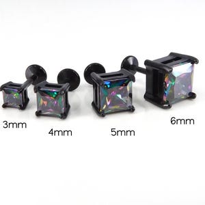 May include: Four black square stud earrings with iridescent, multi-colored gems. Sizes are 3mm, 4mm, 5mm, and 6mm. The earrings have a flat back and a post for piercing.