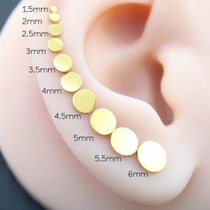 May include: A series of ten gold-colored circular stud earrings arranged in a curved line, ranging in size from 1.5mm to 6mm. Each earring is labeled with its specific diameter measurement, starting from 1.5mm and increasing to 6mm.