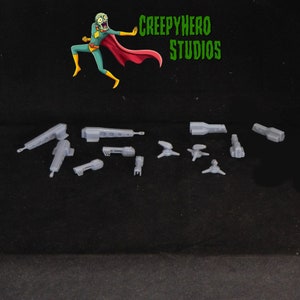 May include: A set of ten gray plastic model pieces for a sci-fi spaceship. The pieces are various shapes and sizes, including a long, thin piece, a round piece, and a piece with a pointed end.